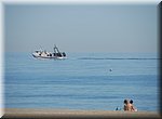 Een vissersboot vaart uit  langs het strand van Torre del Mar