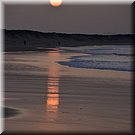De ondergaande zon reflecteert in het natte strand